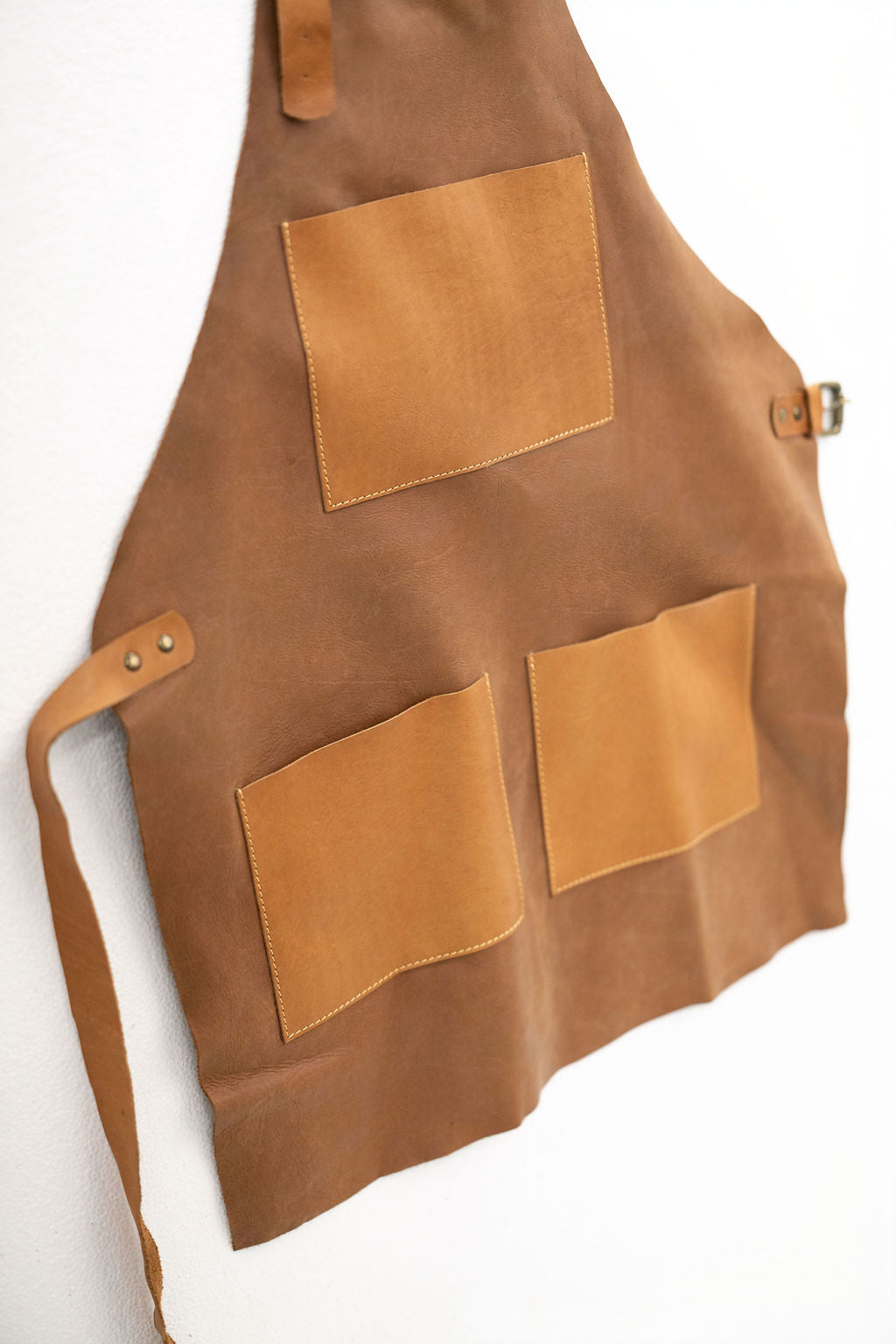 Close-up of CraftLuxe tan leather apron pockets and stitching