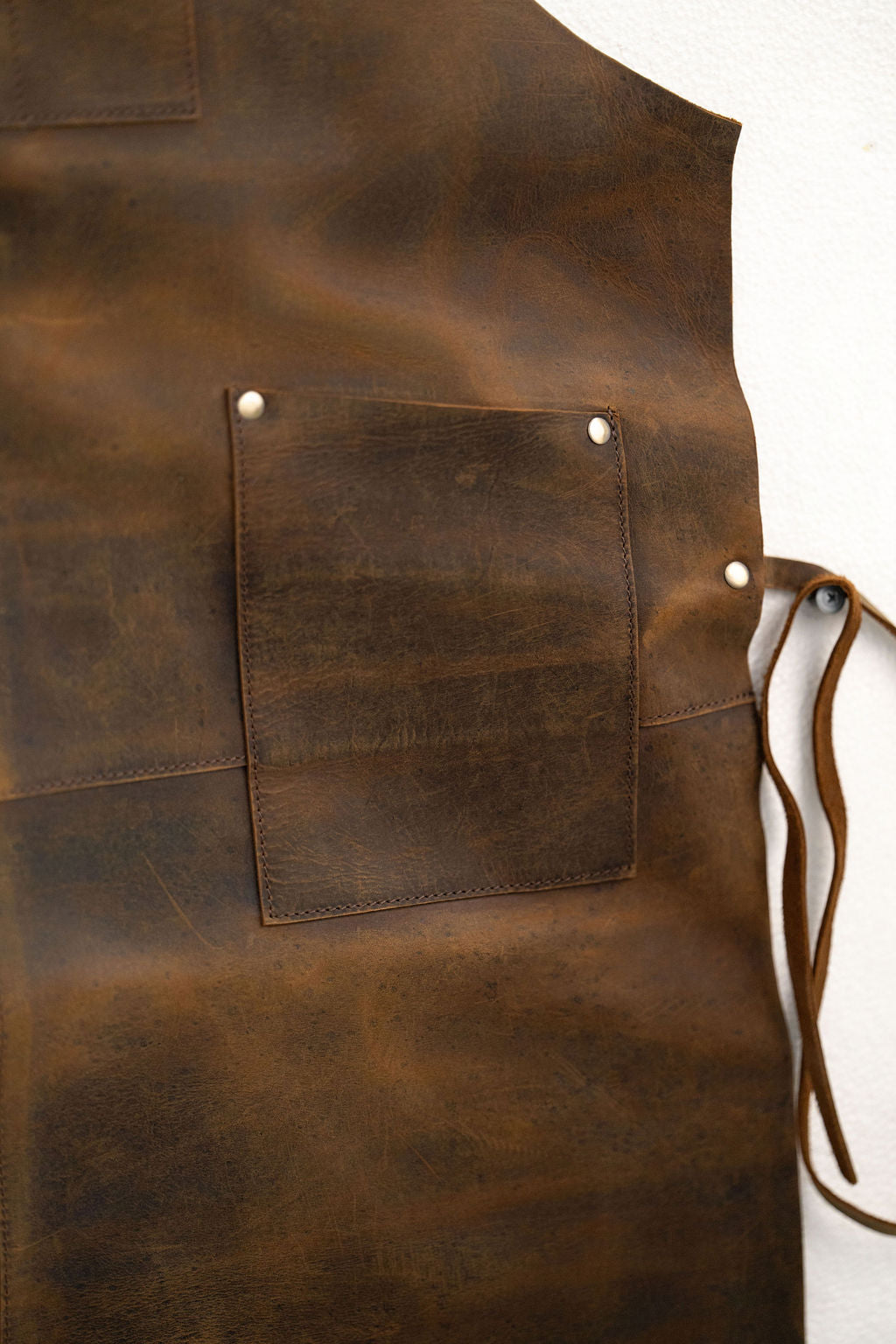 Close-up of CraftLuxe brown leather apron pockets and stitching